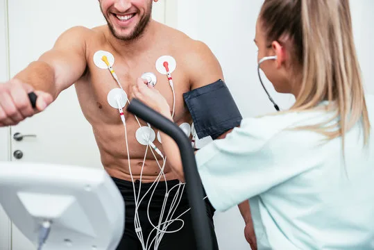 A patient on a treadmill with monitoring electrodes during a cardiac stress test
