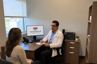 A specialist talking with a patient across a desk in a clinic office